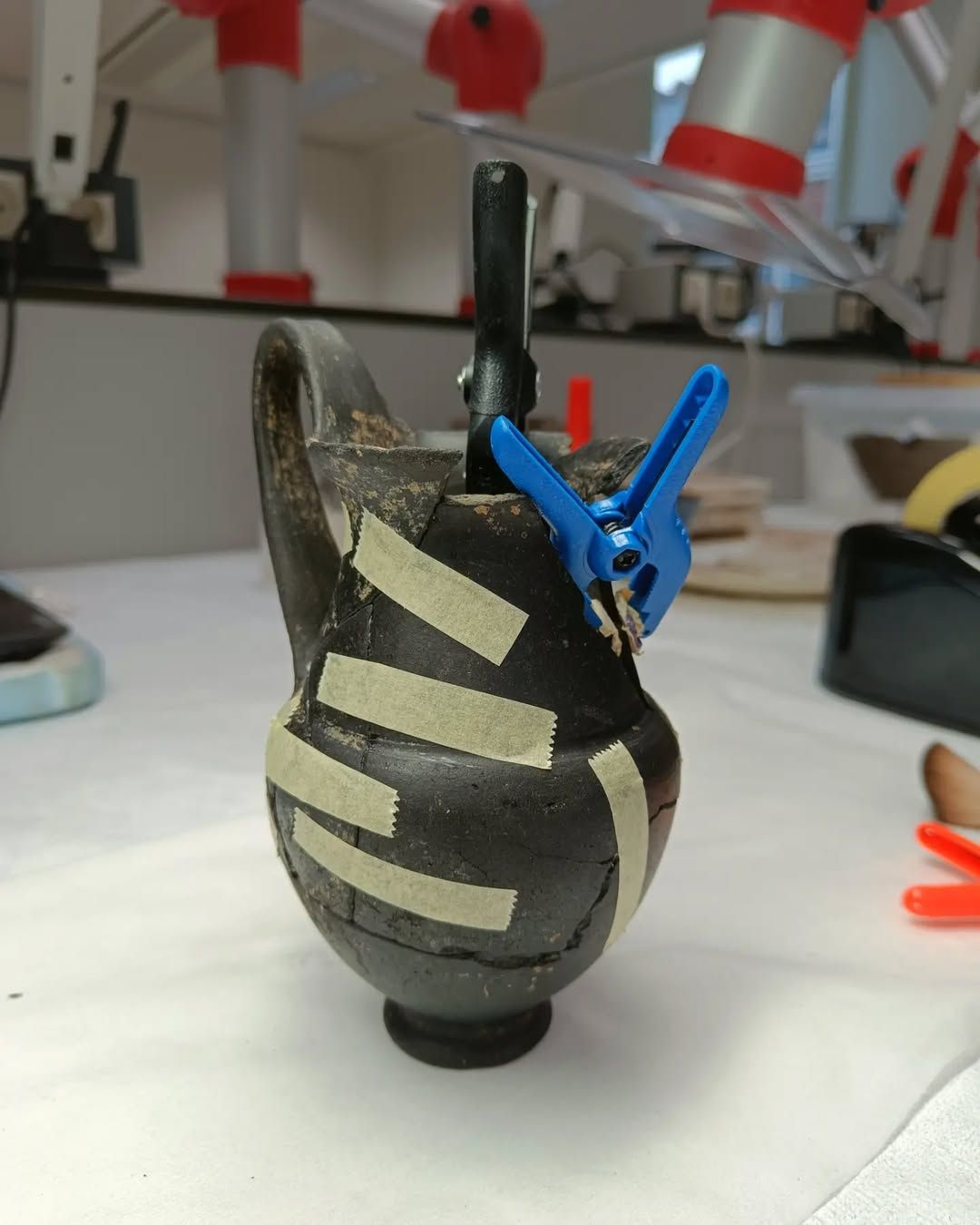 Etruskische Olpe tijdens restauratieproces met tape en klemmen